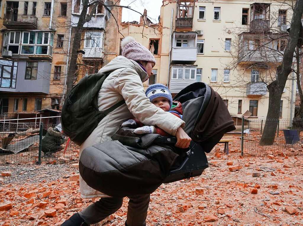 Eine Frau aus Charkiw trgt ihr Kind, whrend sie aus einem Wohnhaus im Stadtzentrum evakuiert wird, das von einer russischen Rakete getroffen wurde.