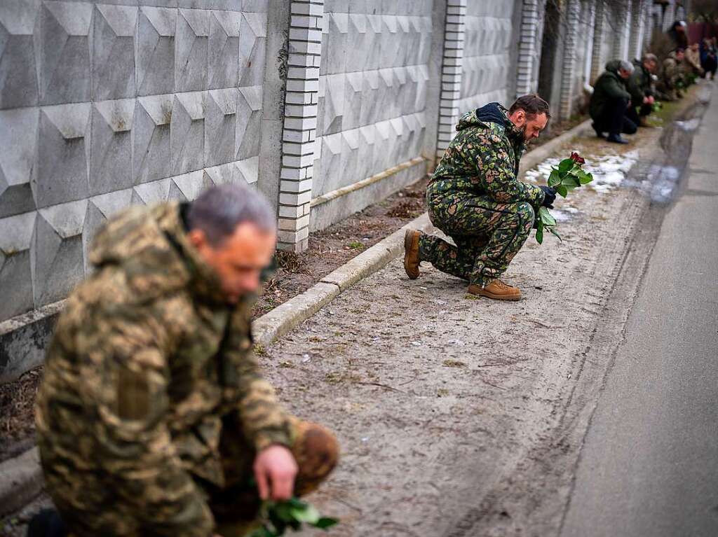 Ukrainische Soldaten knien in  Knjaschytschi nieder, whrend sie darauf warten, dass der Sarg eines getteten Zivilisten vorbeigefhrt wird.