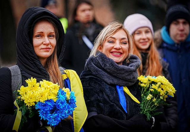 Zwei Frauen mit Blumen in den Farben d...ischen Angriffs auf dem Michaelsplatz.  | Foto: Kay Nietfeld (dpa)