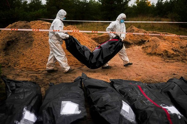 Lyman: Mitglieder eines forensischen T...umierung in einem Massengrab arbeiten.  | Foto: Francisco Seco (dpa)