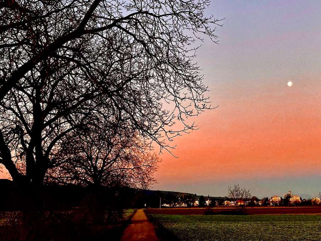 Als kleine Scheibe steht der abnehmende Vollmond am pastellfarbenen Himmel ber Endingen.