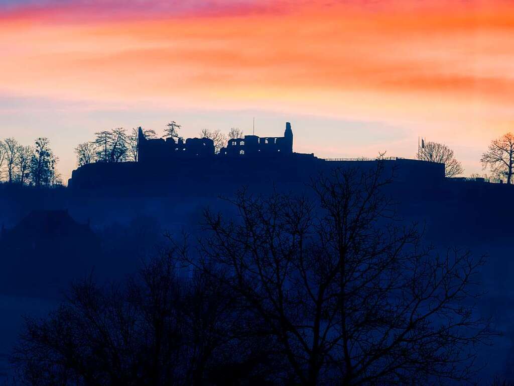 Die Ruine der Hochburg erscheint als Scherenschnitt vor dem dramatischen Himmel.