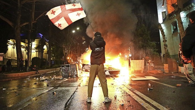 Ein Mann schwenkt eine georgische Nati...einer brennenden Barrikade in Tiflis .  | Foto: Zurab Tsertsvadze (dpa)