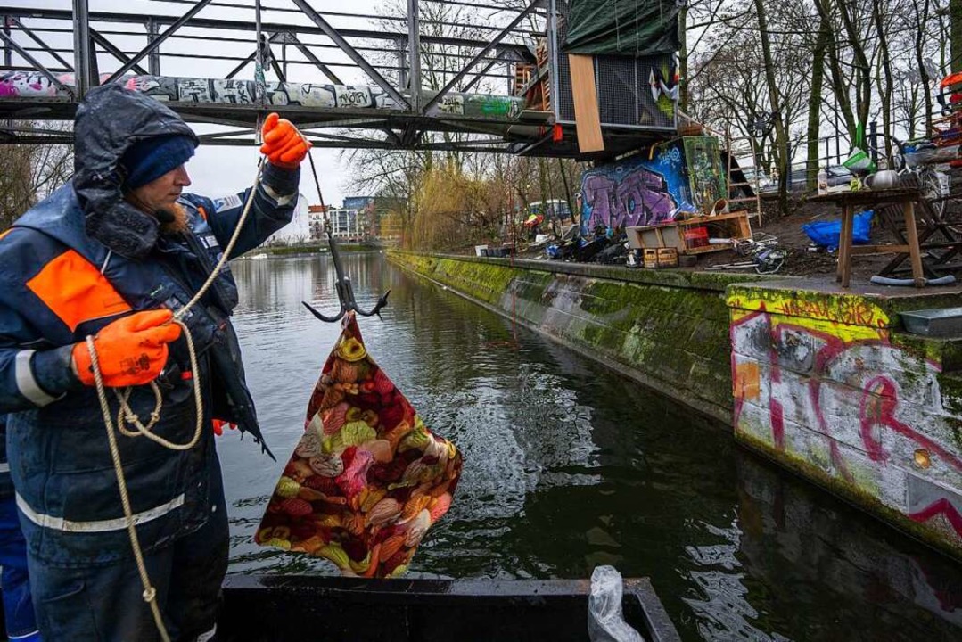 Mit einem Wurfanker zieht er eine Wachstischdecke aus dem Wasser.  | Foto: Monika Skolimowska (dpa)