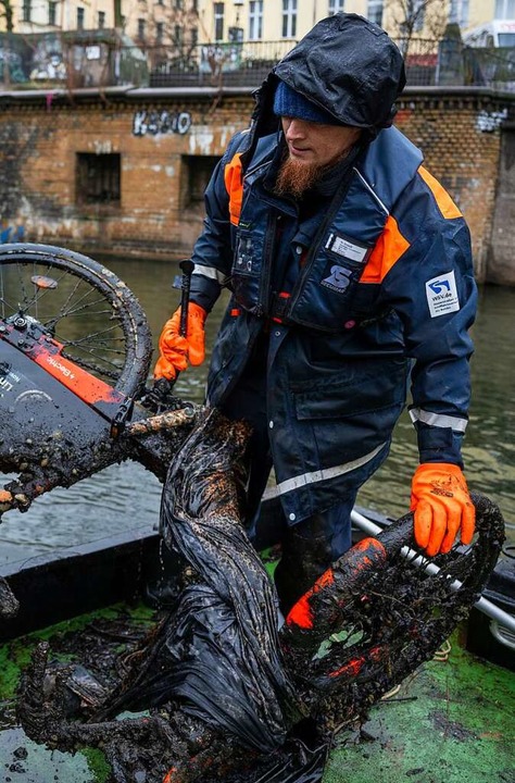 Stephan Strauch, Mitarbeiter vom Wasse...dwehrkanal ein Leihrad aus dem Wasser.  | Foto: Monika Skolimowska (dpa)