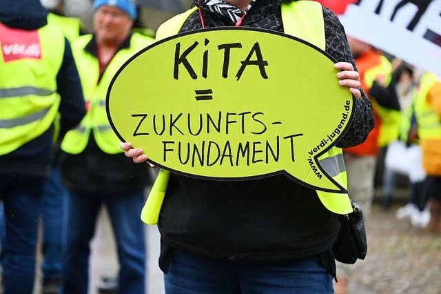 Eine Demonstrantin hlt ein Schild bei...egen am Donnerstag ihre Arbeit nieder.  | Foto: Lars Klemmer (dpa)