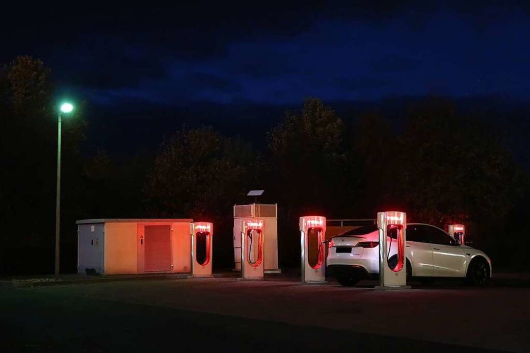 Nur die Ladesäulen leuchten: eine Tesla-Station im Dunkeln  | Foto: Steve Przybilla