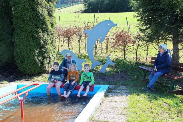 Hans Schaller und seine drei Enkeln vor der Delfin-Skulptur  | Foto: Rolf-Dieter Kanmacher