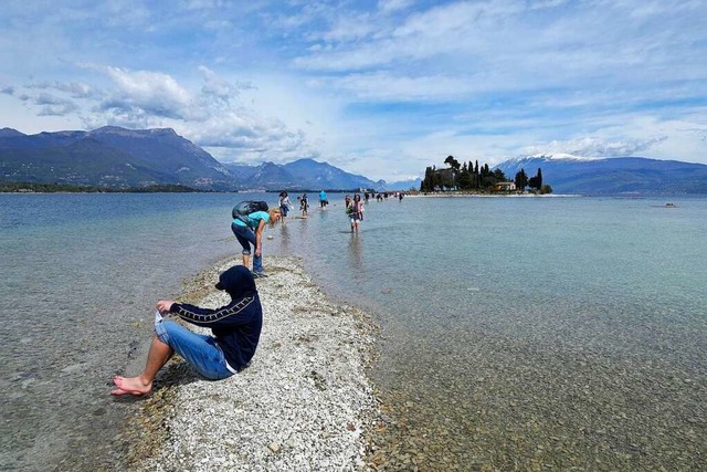 Ein Tourist hlt seineFe in das Was...el San Biagio, am Gardasee, berquert.  | Foto: Luca Bruno (dpa)