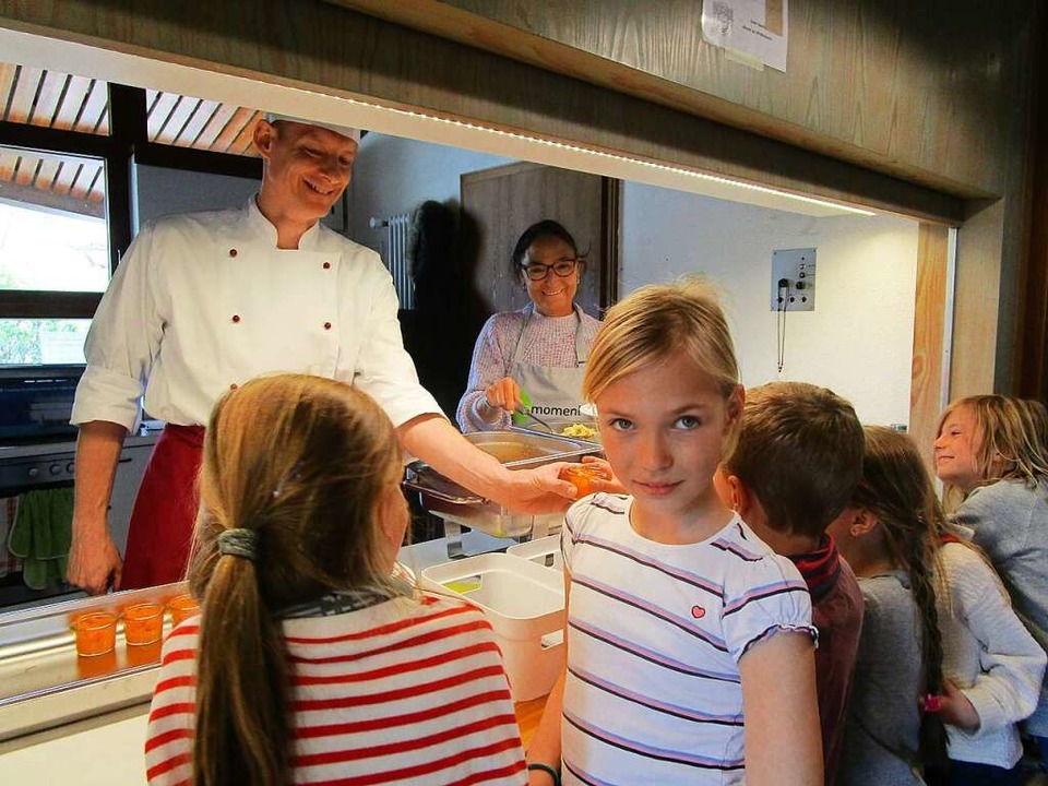 Koch Alexander Schmidt und Birgit Magg...uung reichen Kindern das  Mittagessen.  | Foto: Nicola Hugel