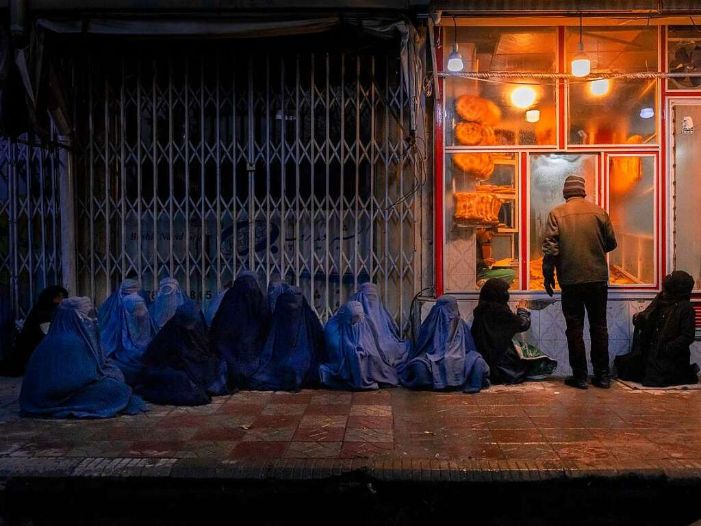 World Press Photo Story of the Year: The Price of Peace in Afghanistan – Mads Nissen. Frau und Kinder betteln vor einer Bckerei im Zentrum Kabuls um Essen. Bevor die Taliban im August 2021 die Macht bernahmen, saen hier hchstens ein paar Frauen und bettelten, aber mit den Monaten nimmt die Verzweiflung zu, und immer mehr Menschen sind nun auf das Mitleid anderer armer Menschen angewiesen. (Foto: Mads Nissen/Politiken/ Panos Pictures/World Press Photo Foundation/dpa)