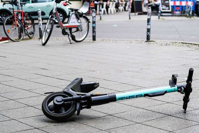 Ein E-Scooter liegt umgekippt mitten a...ei weiter zum Hintergrund des Unfalls.  | Foto: Jens Kalaene (dpa)