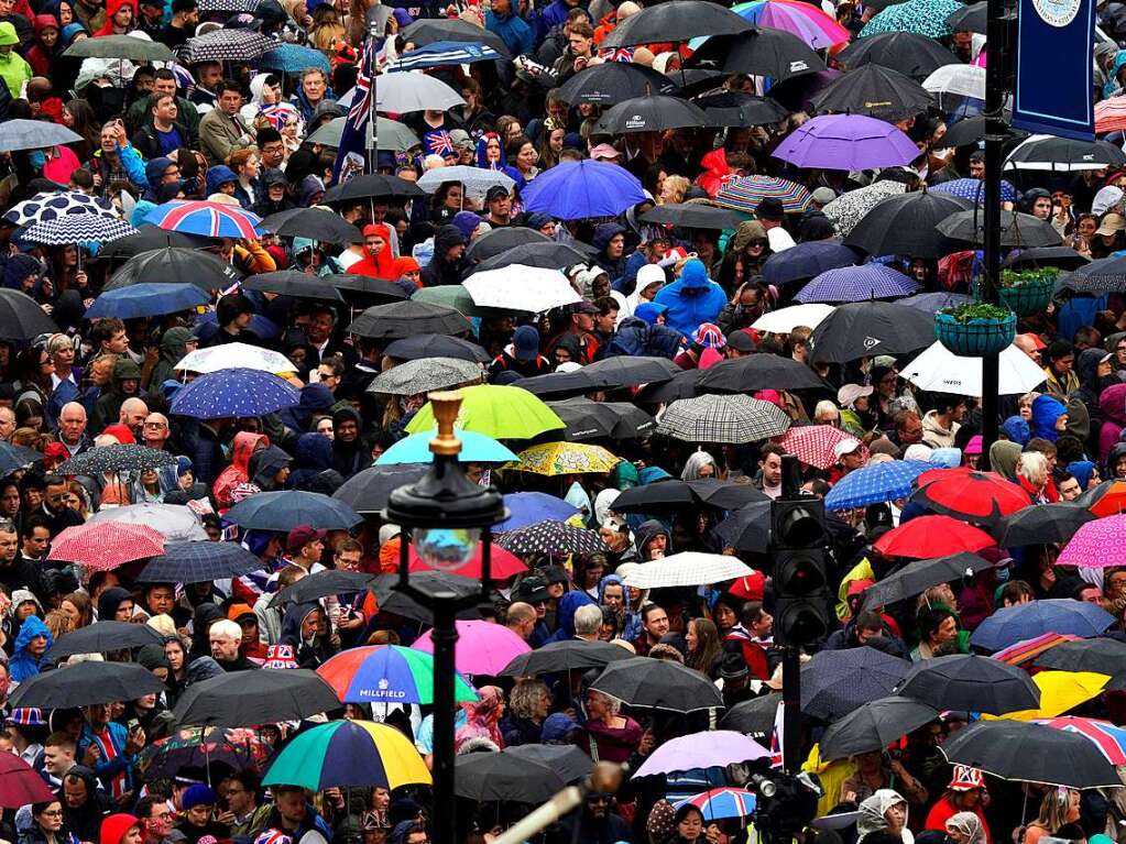 Zahlreiche Menschen zcken wegen des schlechten Wetters ihre Regenschirmen am Trafalgar Square.