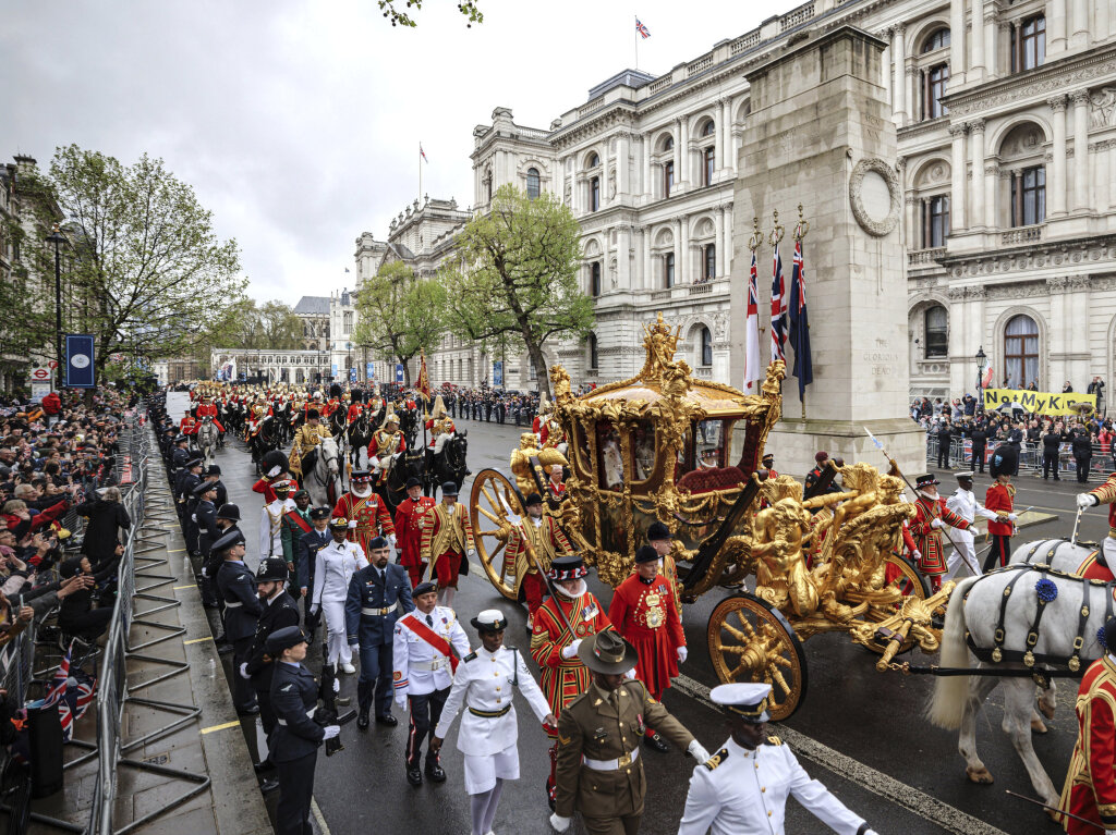 Grobritanniens Knig Charles III. grt die Menge, als er und Knigin Camilla nach ihrer Krnungszeremonie in der Westminster Abbey in der goldenen Staatskutsche zum Buckingham Palace fahren.