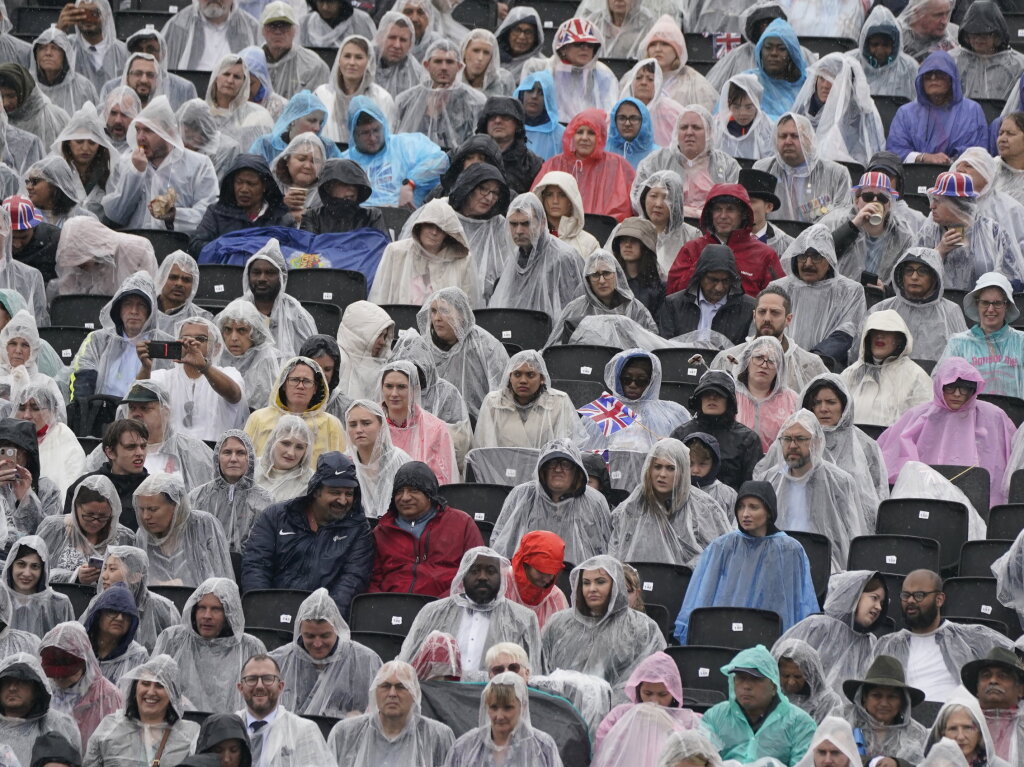 Zuschauer mit Regenponchos auf der Tribne gegenber dem Buckingham Palace warten whrend der Krnungszeremonie von Knig Charles III. und Knigin Camilla.