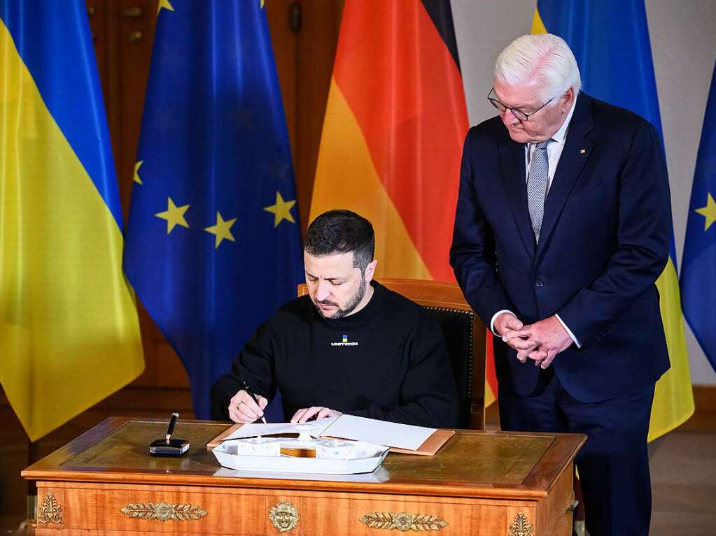 Selenskyj trgt sich vor seinem Gesprch mit Bundesprsident Frank-Walter Steinmeier (rechts) in das Gstebuch im Schloss Bellevue ein.