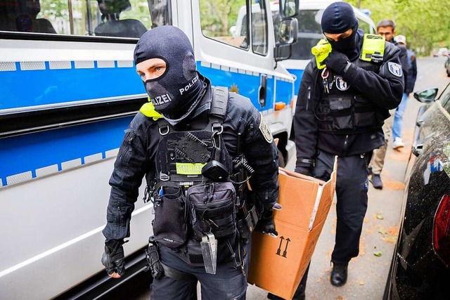 Polizisten tragen bei einer Hausdurchs...te in sieben Bundeslndern durchsucht.  | Foto: Christoph Soeder (dpa)