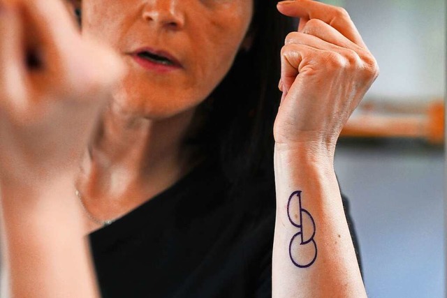 Eine Frau betrachtet das Design ihres neuen Organspende-Tattoos im Spiegel.  | Foto: Pia Bayer (dpa)