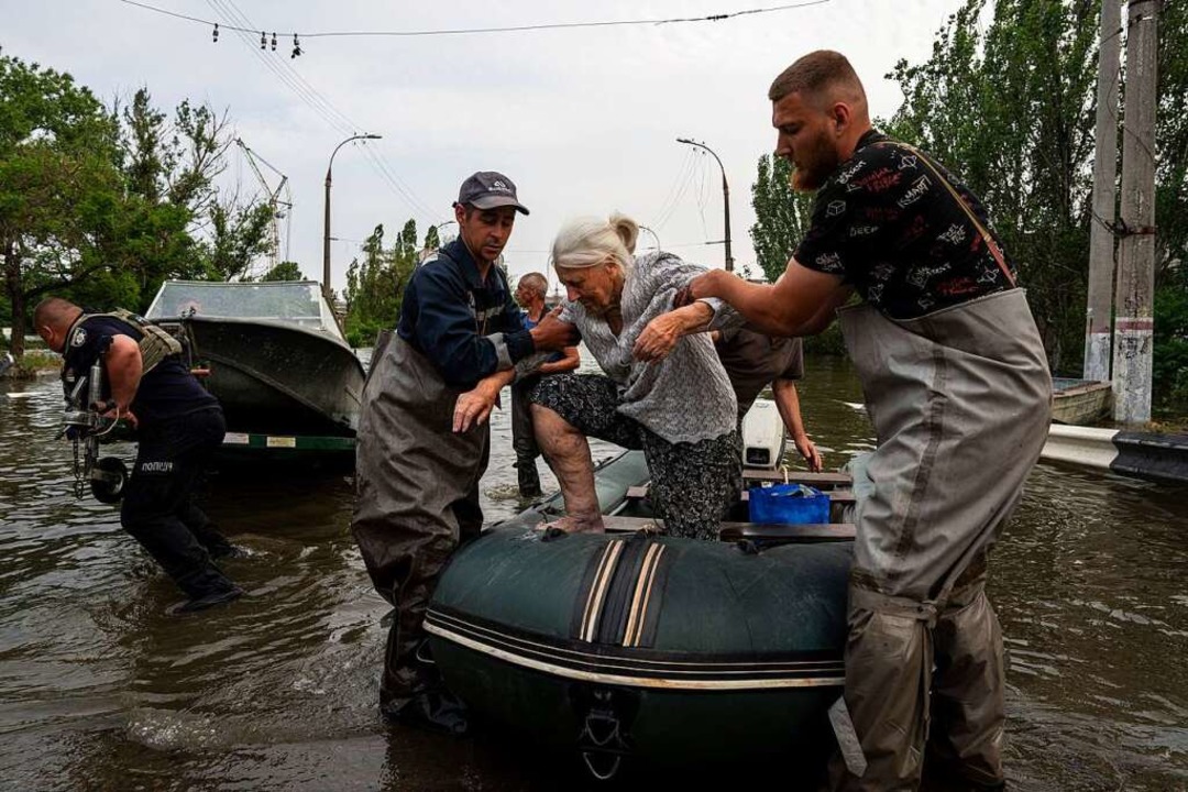 Rettungskrfte evakuieren eine ltere Frau in Cherson.  | Foto: Evgeniy Maloletka (dpa)