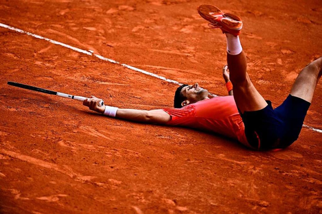 Novak Djokovic liegt nach seinem Finalsieg glücklich im Sand.  | Foto: JULIEN DE ROSA (AFP)