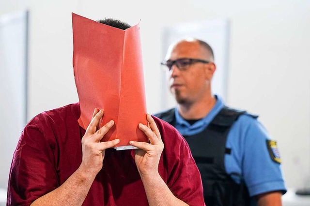 Der Angeklagte verbirgt sein Gesicht hinter einer Aktenmappe.  | Foto: Boris Roessler (dpa)