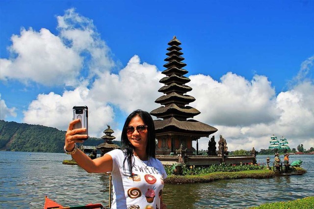 Eine Touristin macht ein Selfie vor dem Ulun Danu Bratan Water Temple auf Bali.  | Foto: Andri (stock.adobe)