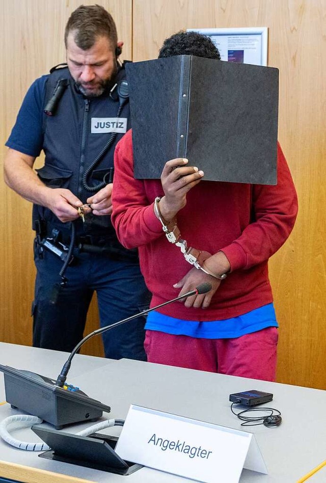 Der Tter verdeckt im Gerichtssaal sein Gesicht mit einem Aktenordner.  | Foto: Stefan Puchner (dpa)