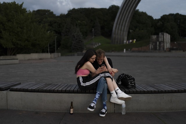 Kiew: Ein Paar kuschelt auf einer Bank...n Video auf einem Smartphone anschaut.  | Foto: Jae C. Hong (dpa)