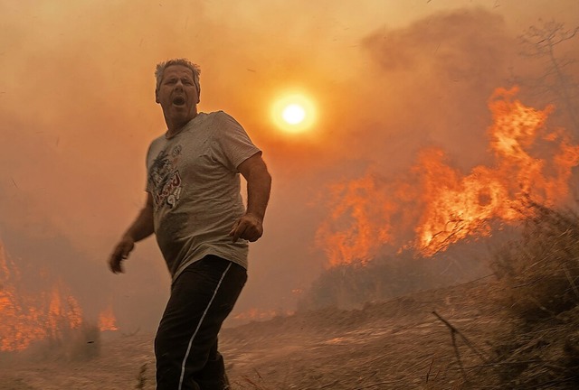 Ein Einheimischer flieht vor den Flamm...dosten der griechischen Insel Rhodos.  | Foto: Petros Giannakouris (dpa)