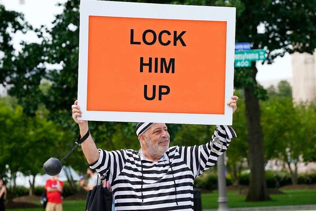 Ein Mann hlt ein Schild mit der Aufsc... Ex-US-Prsident vor Gericht erwartet.  | Foto: Jacquelyn Martin (dpa)