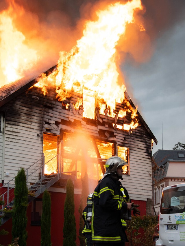 Feuerwehrleute vor der brennenden Ferienunterkunft in Wintzenheim  | Foto: Patrick Kerber (dpa)