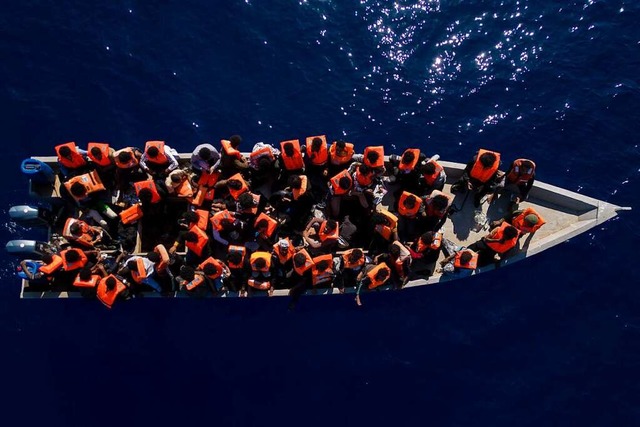 Migranten aus Eritrea, Libyen und dem Sudan sitzen in einem Holzboot.  | Foto: Joan Mateu Parra (dpa)
