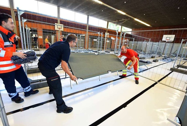 Ehrenamtliche installieren Betten in der Turnhalle.  | Foto: Rita Eggstein