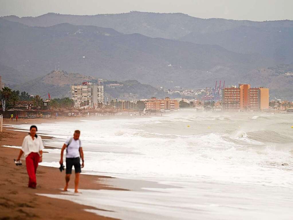 Menschen sind  am Strand von Torremolinos unterwegs.