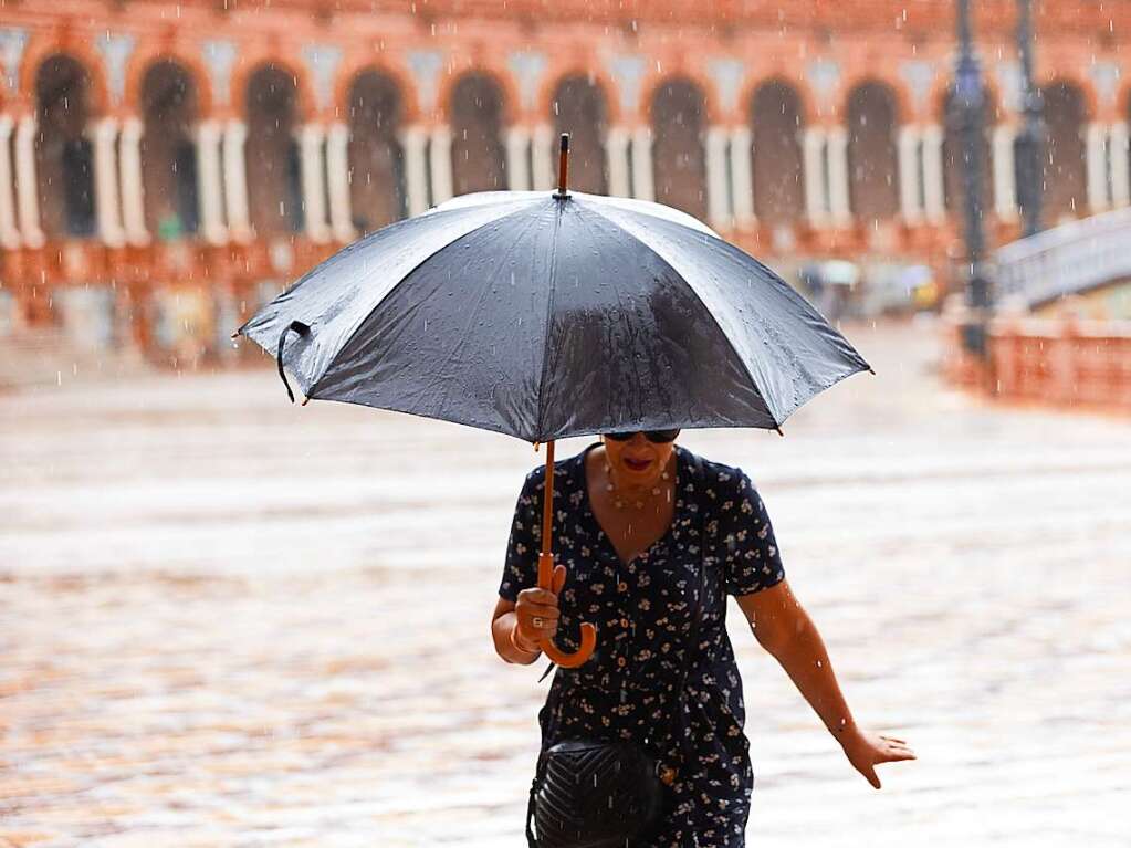 Eine Fugngerin schtzt sich mit einem Regenschirm vor dem Regen auf der Plaza de Espana in Sevilla. Die Behrden haben fr die nchsten Tage landesweit auergewhnlich heftige Regenflle angekndigt.