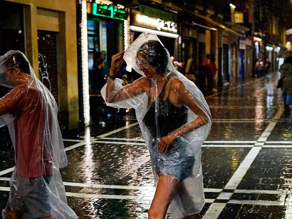 Menschen gehen bei starken Regen in einer Fugngerzone in Pamplona.