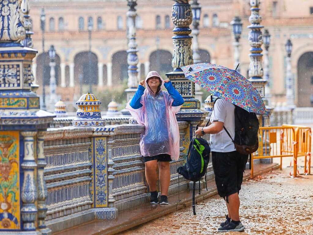 Fugnger schtzen sich vor dem Regen auf der Plaza de Espaa in Sevilla.