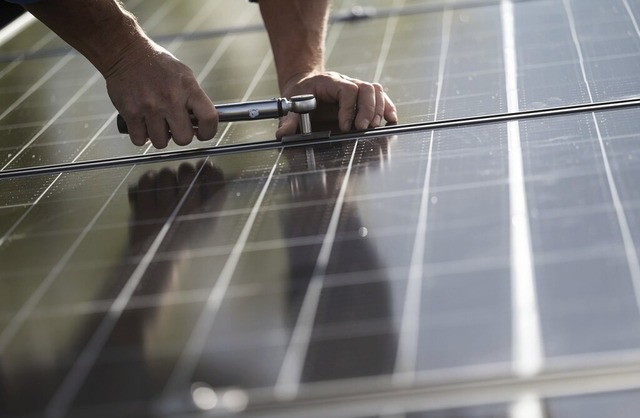 Ein Handwerker montiert Photovoltaikmodule auf dem Dach eines Wohnhauses.  | Foto: Marijan Murat (dpa)