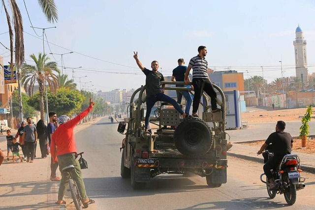 Palstinenser fahren in der Nhe der G...uf einem israelischen Militrfahrzeug.  | Foto: Abed Abu Reash (dpa)