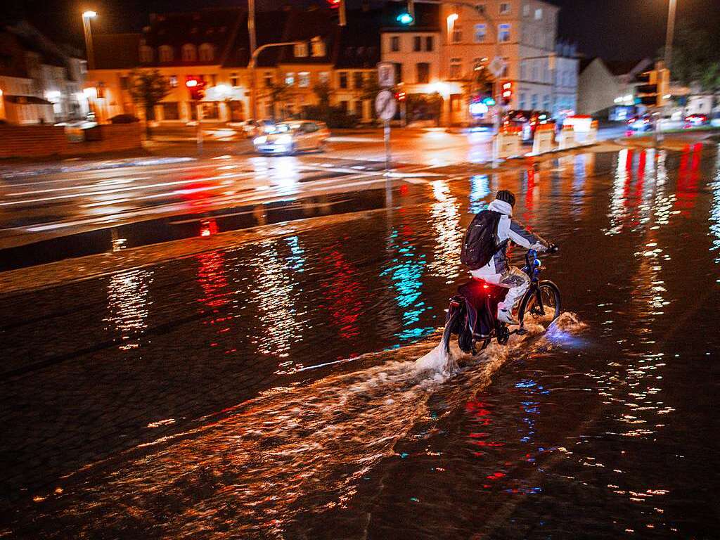 Freitagmorgen: In Wismar in Mecklenburg-Vorpommern fhrt ein Radfahrer durch das Hochwasser am Stadthafen.