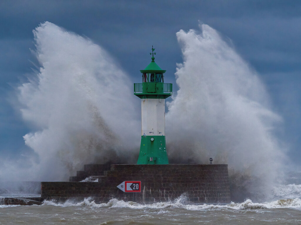 Wellen der Ostsee peitschen bei einem schweren Sturmtief an den Leuchtturm auf der Ostmole in Sassnitz, Mecklenburg-Vorpommern.