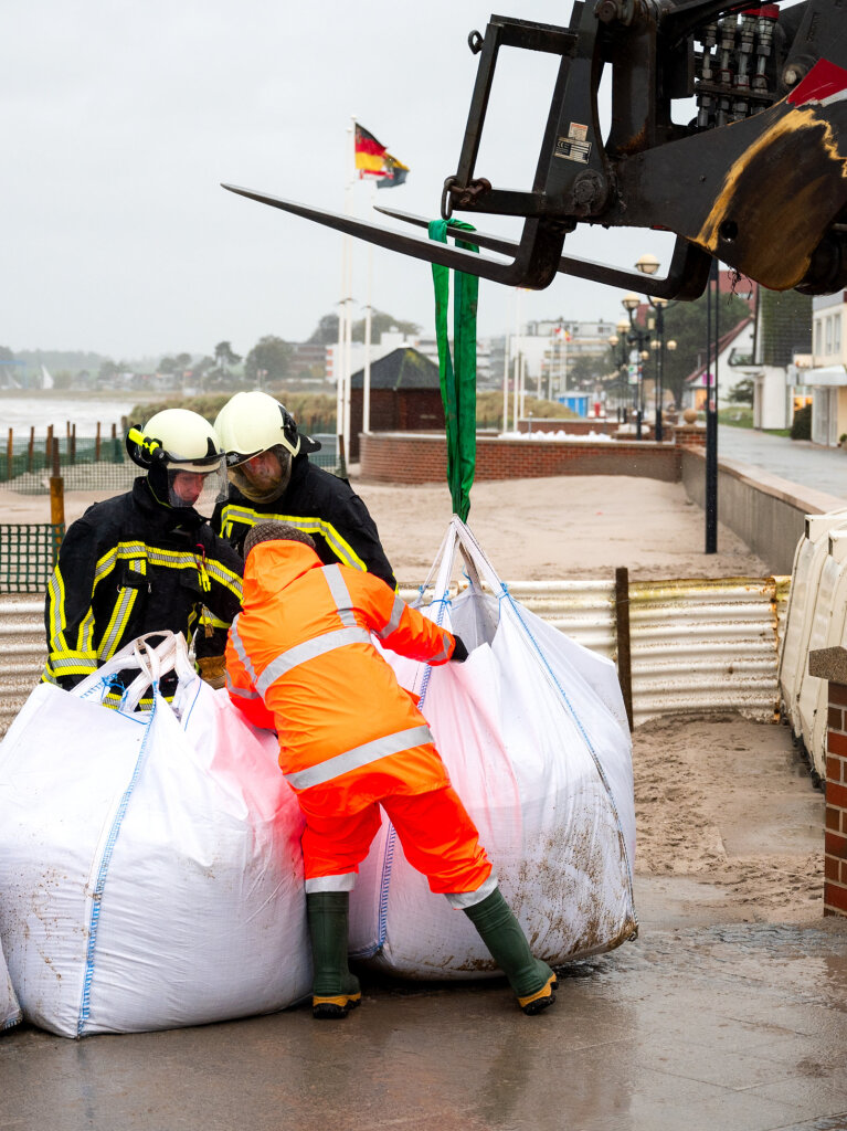 In Grmitz in Schleswig-Holstein versperren Feuerwehrleute den Strandzugang gegen das Wasser der Ostsee