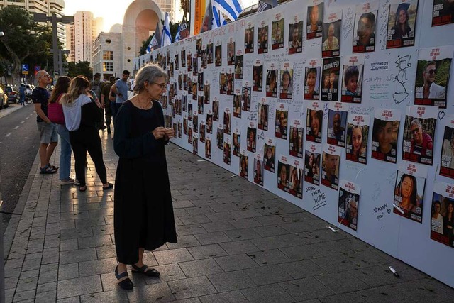 Menschen betrachten in Tel Aviv Fotos ...Jetzt sind zwei von ihnen wieder frei.  | Foto: Petros Giannakouris (dpa)