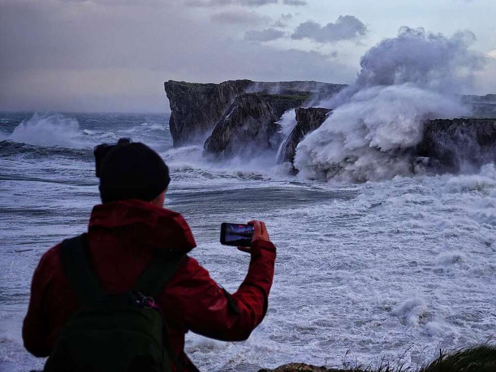 Spanien, Llanes, Asturien: Eine Person fotografiert die hohen Wellen.