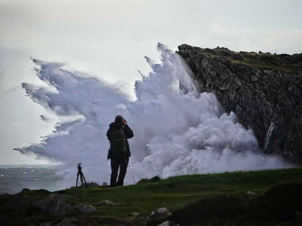 Spanien, Llanes, Asturien: Eine Person fotografiert die Wellen.