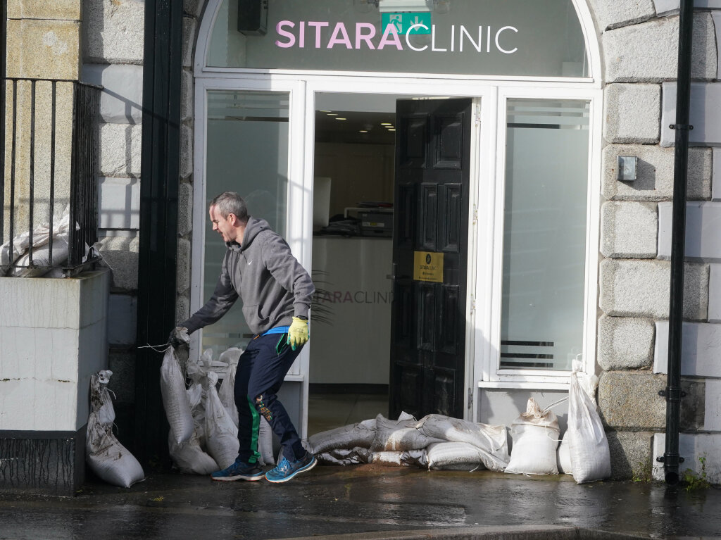 Grobritannien, Merchants Quay: Ein Mann platziert Sandscke vor einem Geschft.