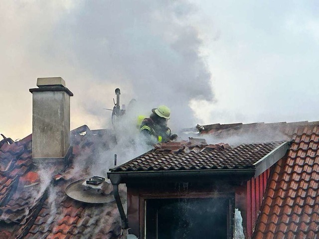 Ein Feuerwehrmann  im Rauch auf einem Dach im Dachsweg.   | Foto: Helmut Seller