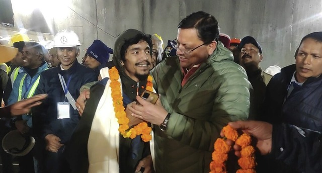 Pushkar Singh Dhami (rechts), Minister...r, der aus dem  Tunnel gerettet wurde.  | Foto: Uncredited (dpa)