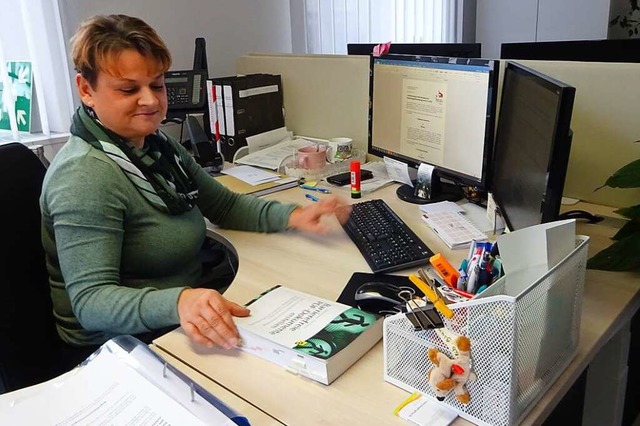 Beate Einecker sitzt an ihrem Schreibt...itige Handbuch griffbereit neben sich.  | Foto: Alexander Steinmeier