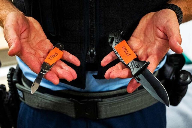 Ein Bundespolizist zeigt sichergestellte Messer.  | Foto: Daniel Bockwoldt (dpa)